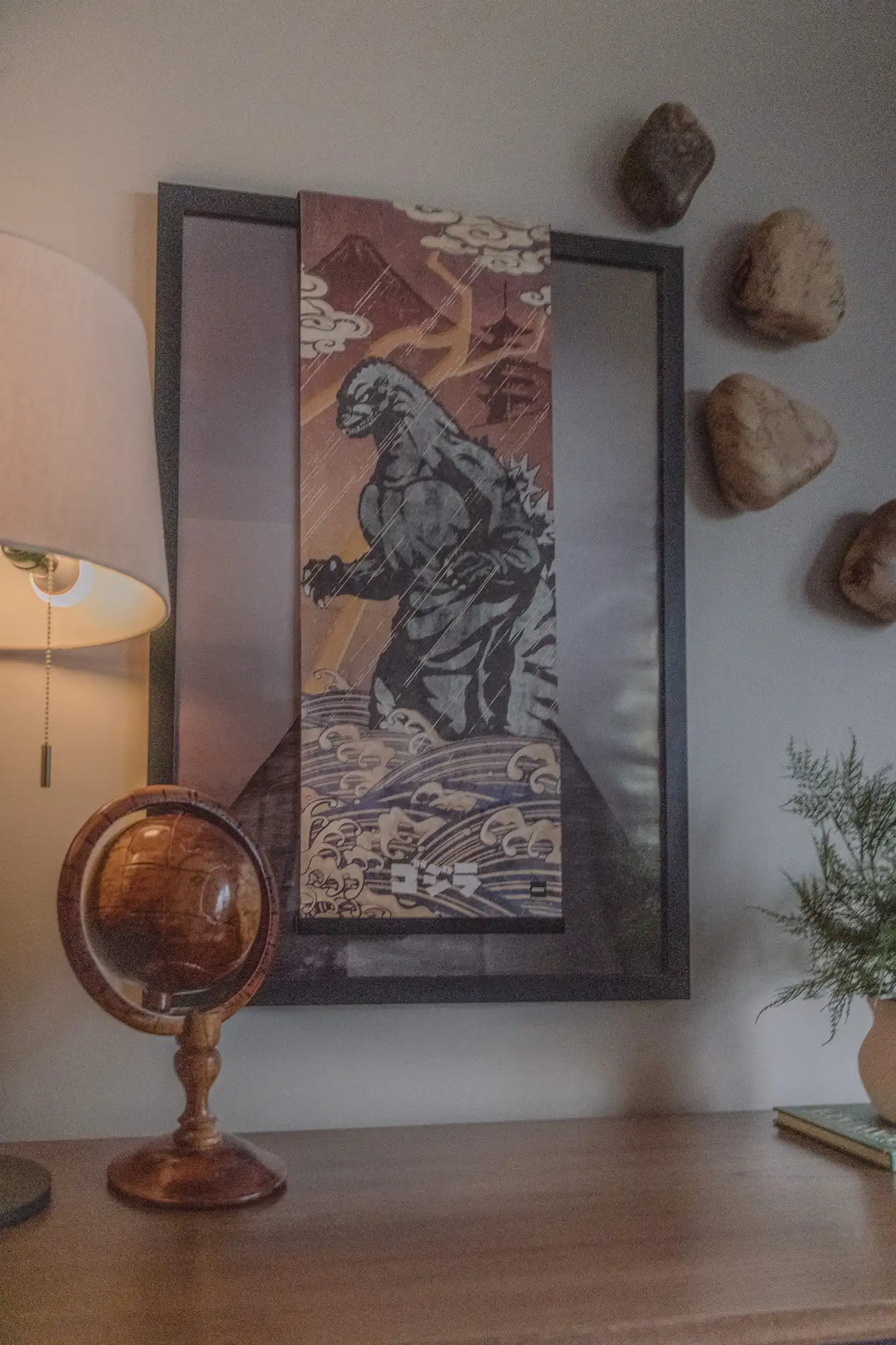 Framed wave artwork and woven wall accents above a dresser with a globe