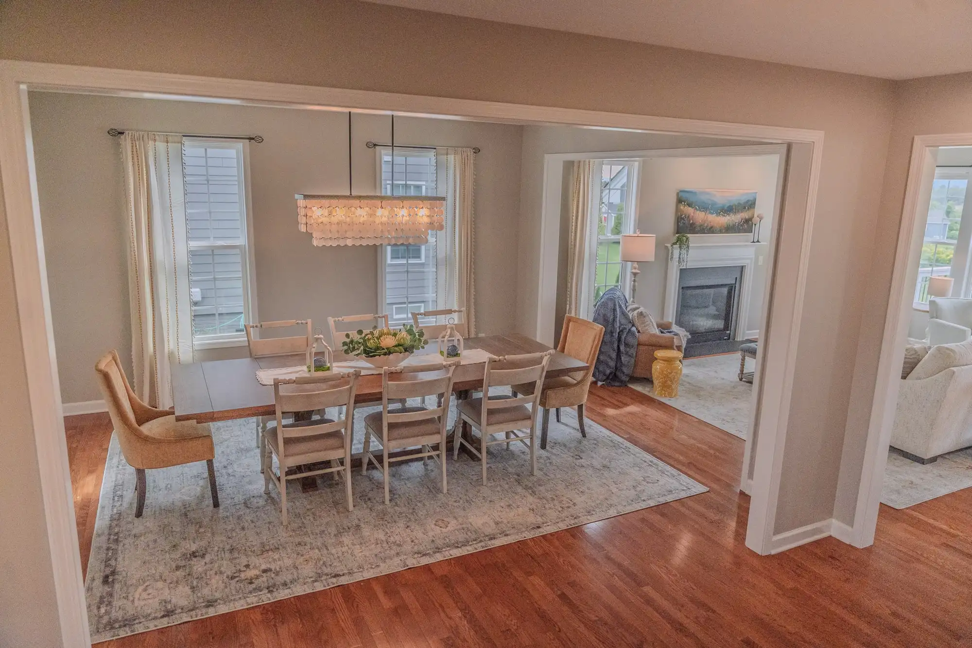 Dining table with upholstered chairs and a rectangular chandelier beside the living room