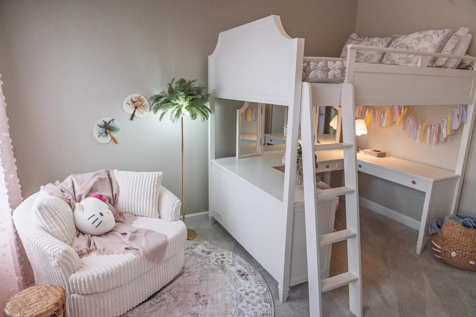 White loft bed with a desk beneath, a pale pink chair, and flower-shaped wall decorations