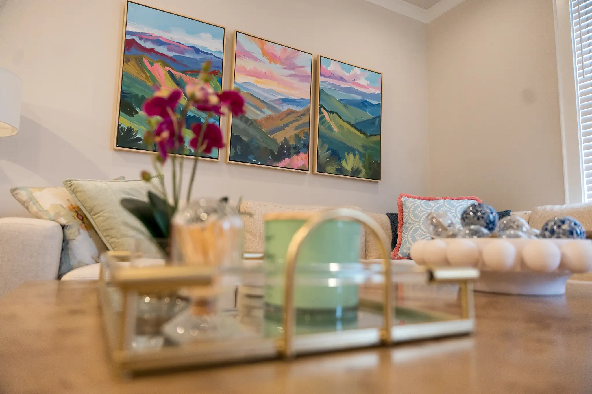 Colorful landscape paintings above a sofa with patterned pillows