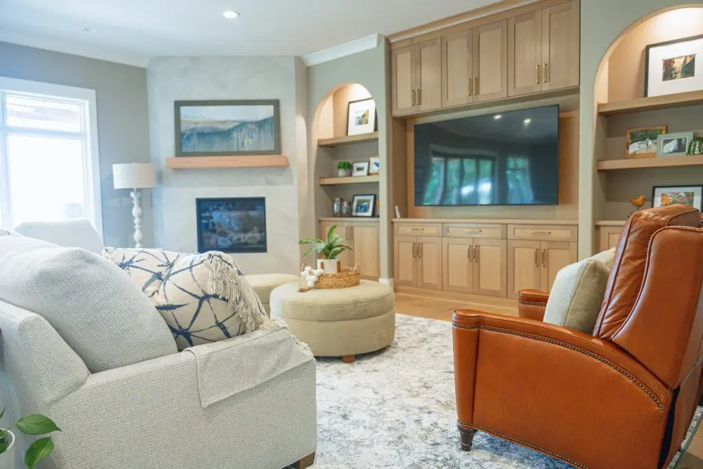 Living room with arched wood shelves, pale upholstery, and a cognac leather chair