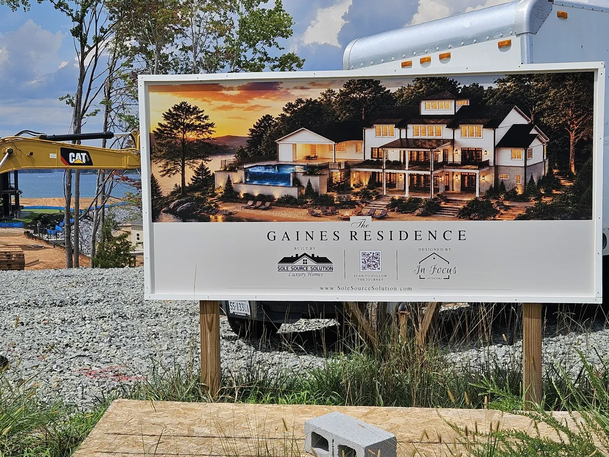 Construction site with a large Gaines Residence sign and a CAT excavator arm nearby.